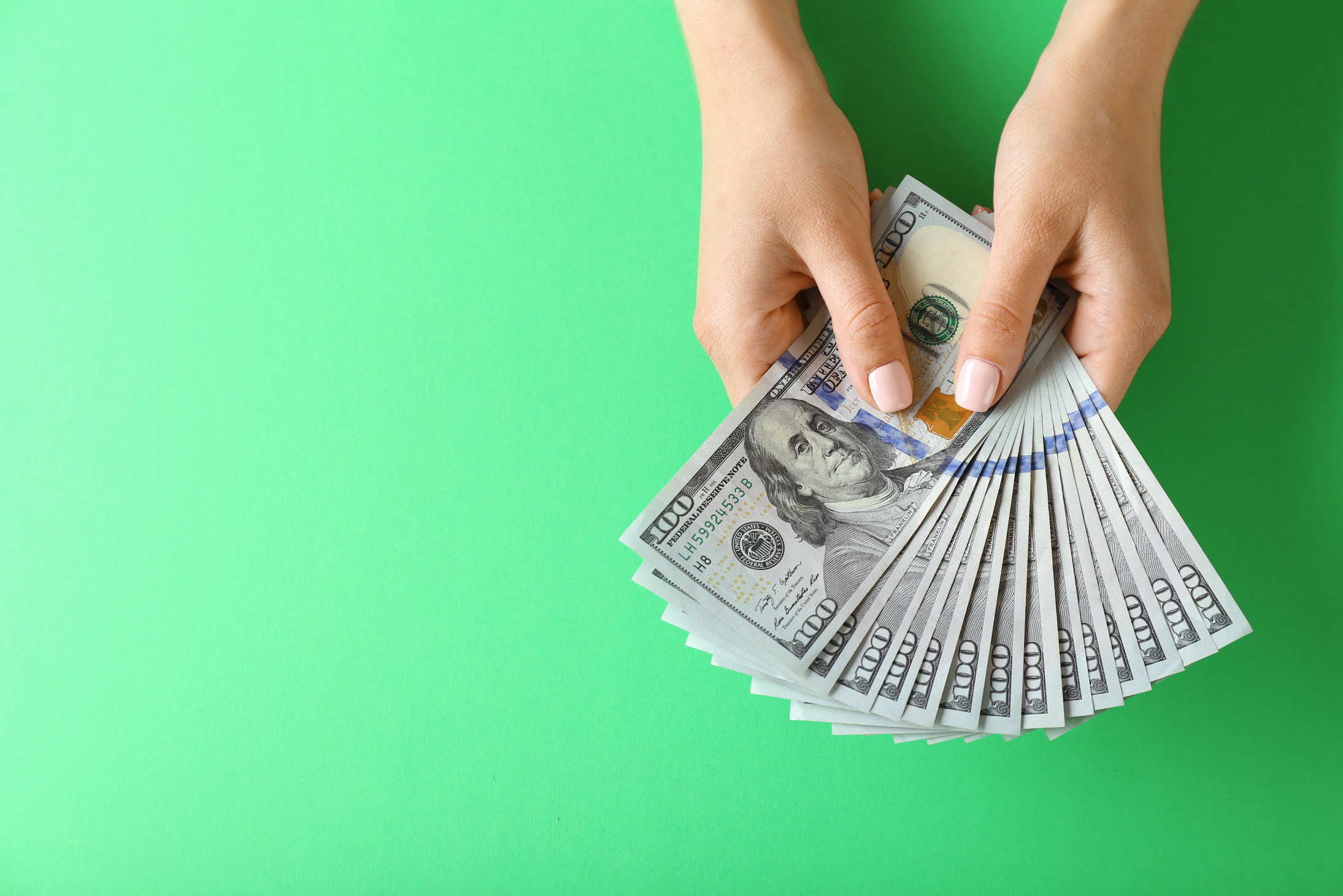 Person Hands Holding Money on Green Background